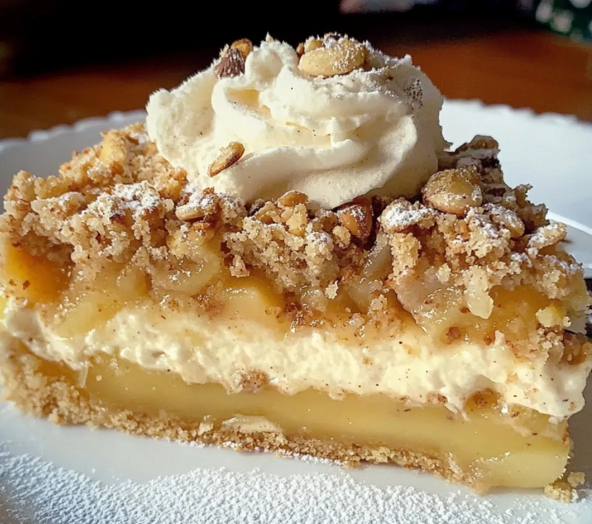 Ein Stück Apfel-Nusskuchen mit Vanillepudding auf einem weißen Teller.