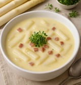 Ein weißer Becher mit Spargelcremesuppe.